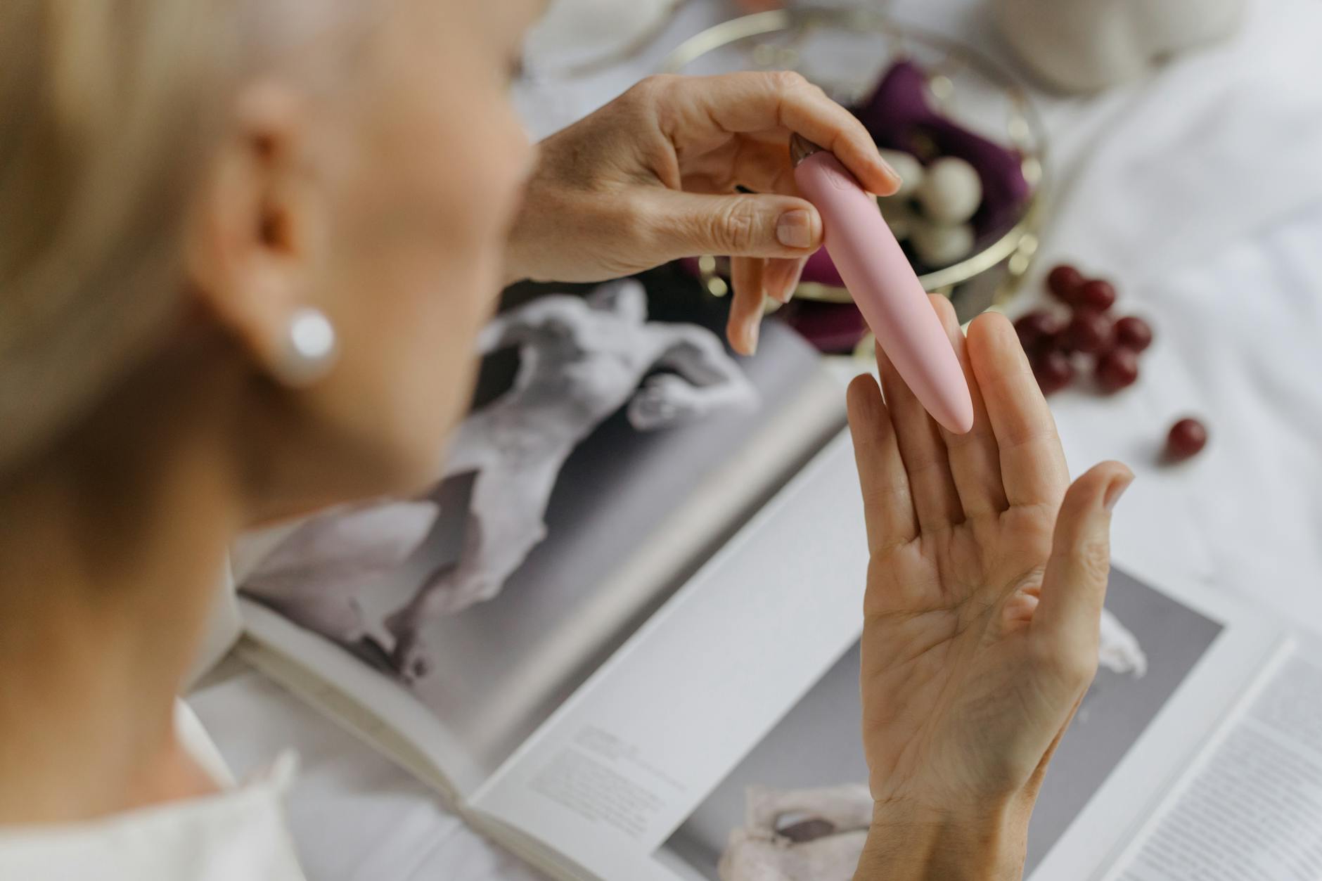 Person holding blue and pink silicone clitoral vibrators in contemplative hands