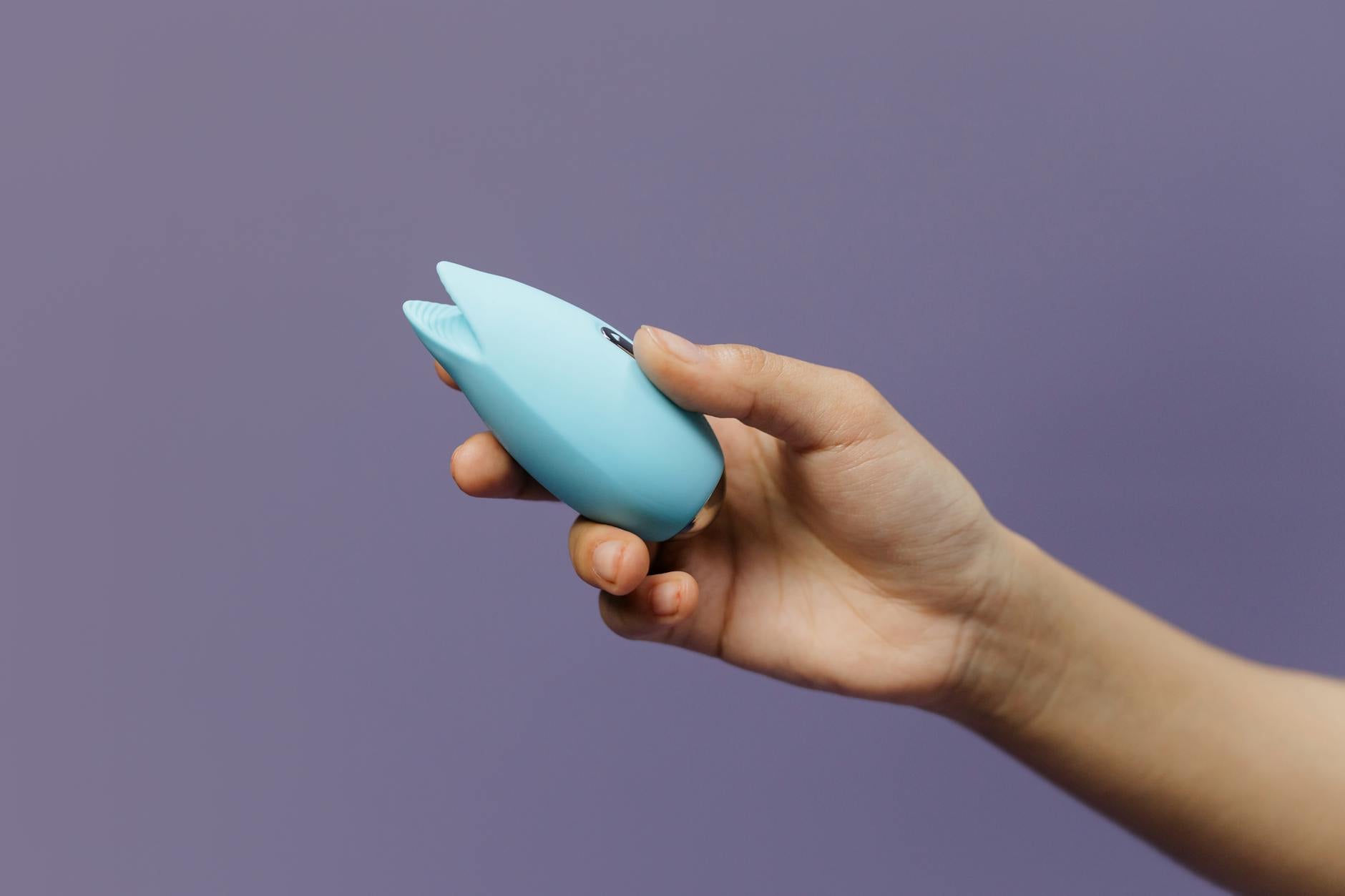 A young couple standing together indoors, holding a blue vibrator, symbolizing modern intimacy and shared pleasure.